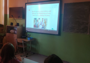 Dzieci oglądające prezentację na tablicy multimedialnej.